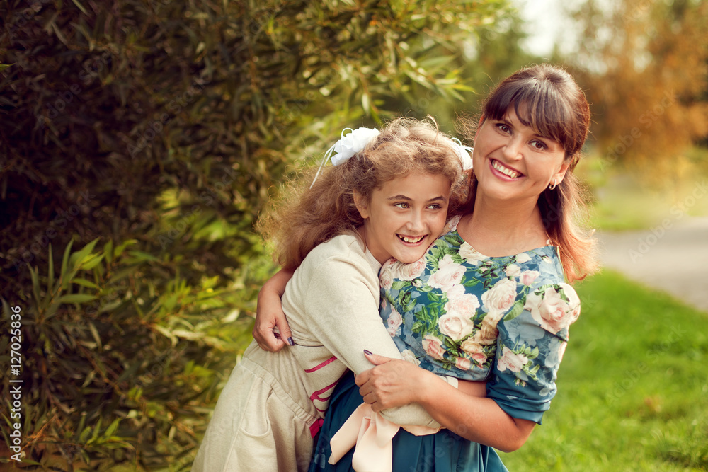 Beautiful young mother in a floral dress and daughter teen 10 ye