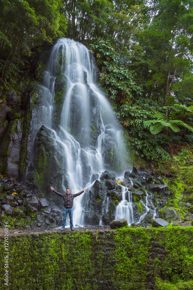 man with open arms in front of a big waterfall