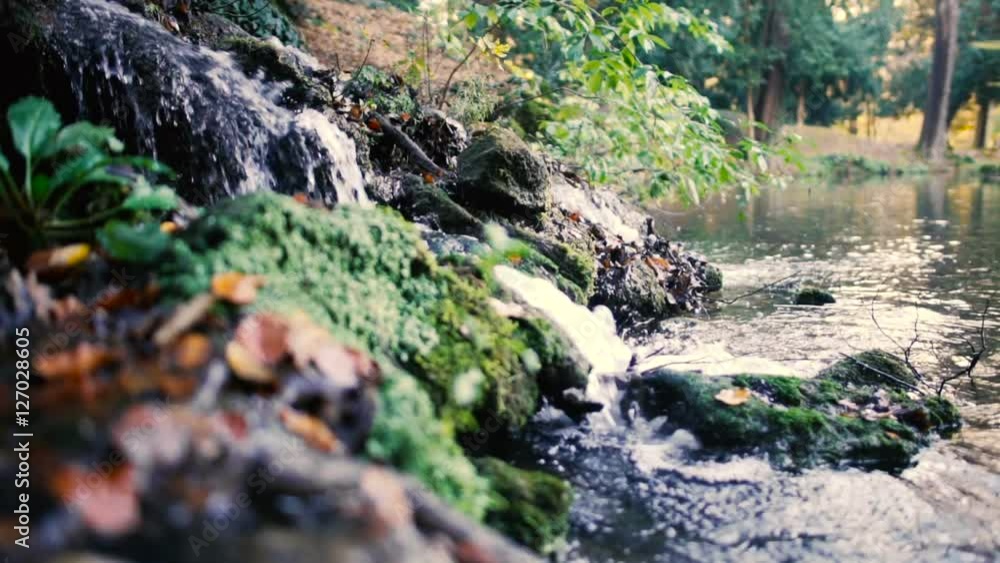 Small waterfall in autumn in slow motion with leaves rocks and vegetation Small waterfall in autumn in slow motion with leaves rocks and vegetation