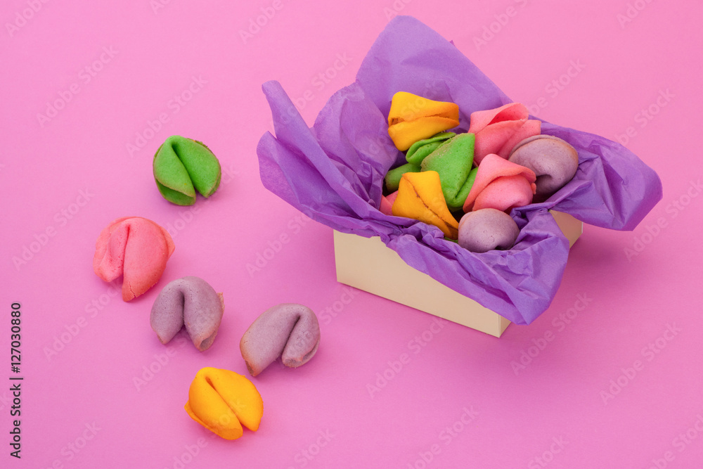 many colored cookies in the shape of seashells on a pink background and a box many colored cookies in the shape of seashells on a pink background and a box