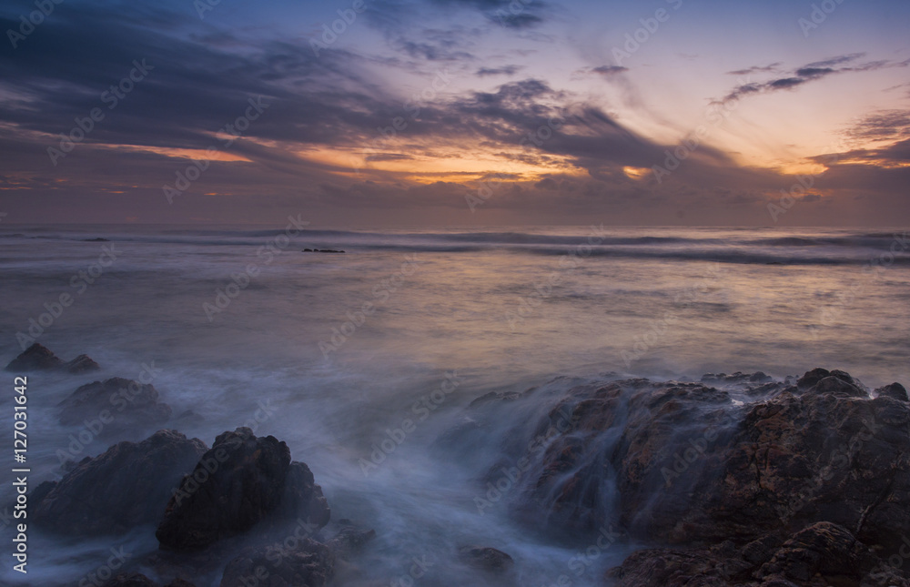 sunset at beach with rocks and sky with clouds sunset at beach with rocks and sky with clouds