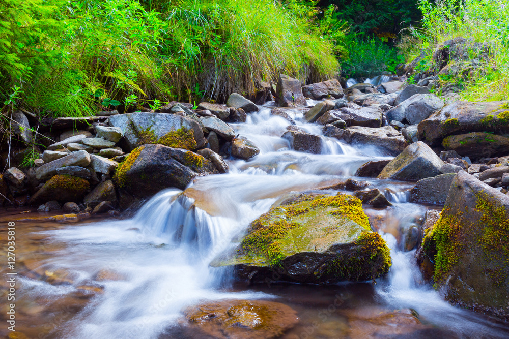 Mountain stream(creek) in the stones and green grass banks in mountain forest. Crystal clear water - rare condition of modern enviroment. Long exposure. Mountain stream(creek) in the stones and green grass banks in mountain forest. Crystal clear water - rare condition of modern enviroment. Long exposure.