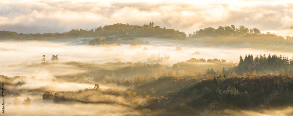 Fototapeta premium Aerial view of valley covered in layers of fog on a beautiful Autumn morning in the Lake District.