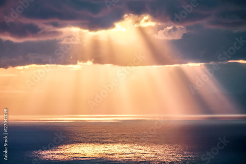Fototapeta Rays of light after rain storm, seascape with sun reflections on water surface