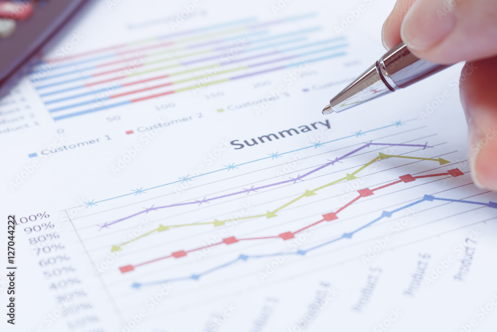Close up businessman holding pen is on summary report and calcul Close up businessman holding pen is on summary report and calcul
