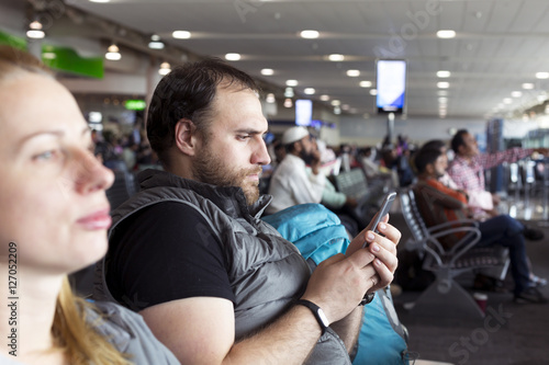 Man and woman at airport terminal using mobile phone