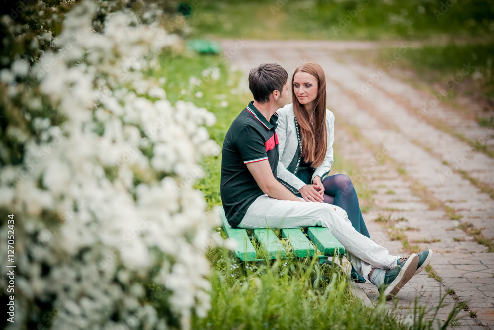 Dating. Young woman and man walking, couple in love relaxing in blossoming trees park at sunny spring day Dating. Young woman and man walking, couple in love relaxing in blossoming trees park at sunny spring day