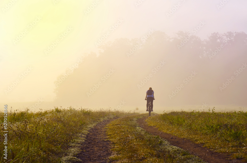 Alone girl on bicycle riding through morning misty nature, Original sport wallpaper