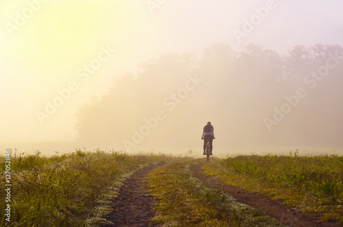 Alone girl on bicycle riding through morning misty nature, Original sport wallpaper