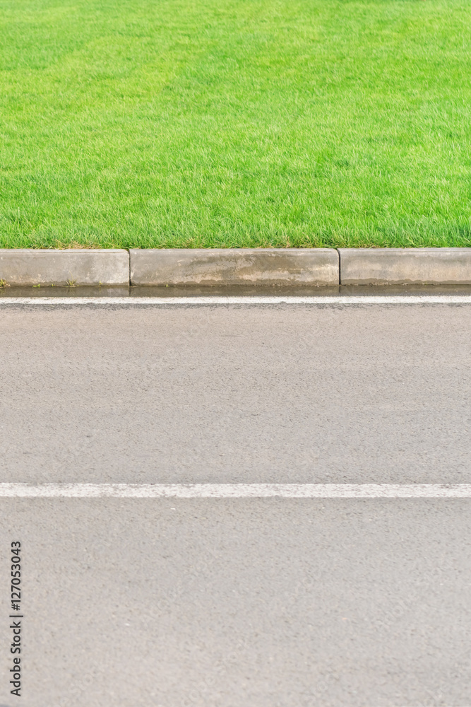 Fototapeta premium Part of an asphalt road with a border and a green lawn