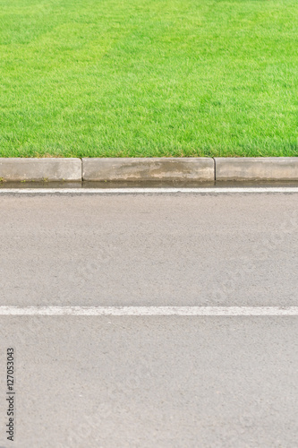Part of an asphalt road with a border and a green lawn © watman