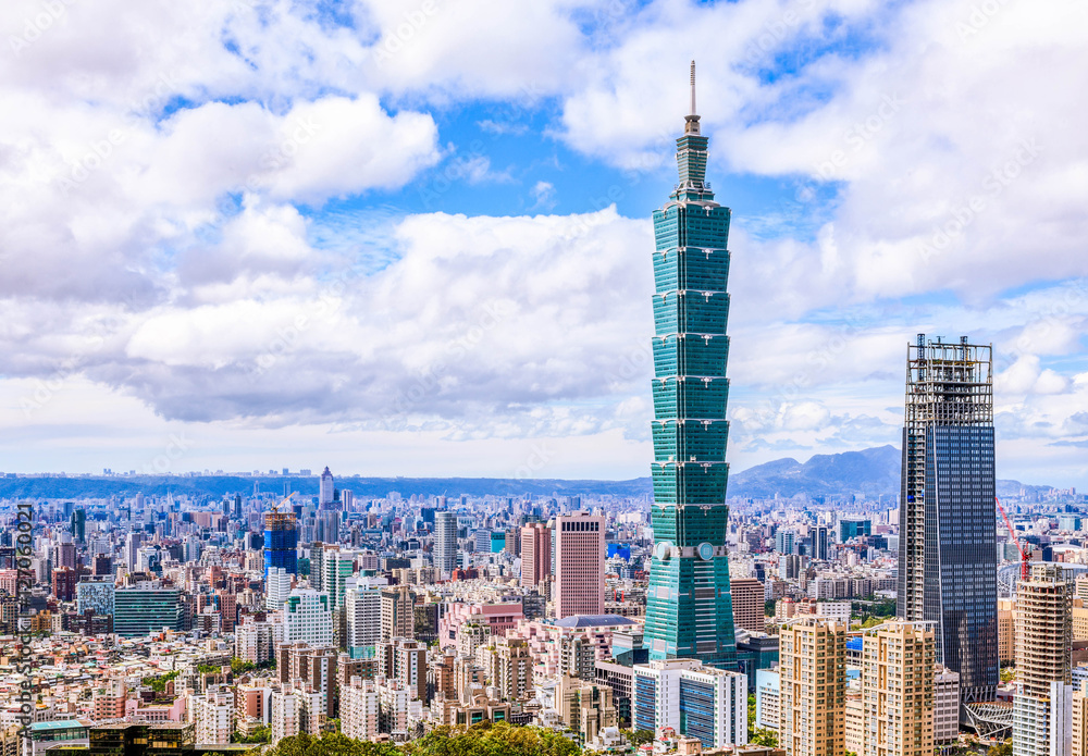 Aerial panorama over Downtown Taipei, capital city of Taiwan with view of prominent Taipei 101 Tower amid skyscrapers in Xinyi Financial District & overcrowded buildings in city center under sunny sky