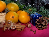 новогодние мандарины лежат на красном фоне с веточками ели  и шишкой       