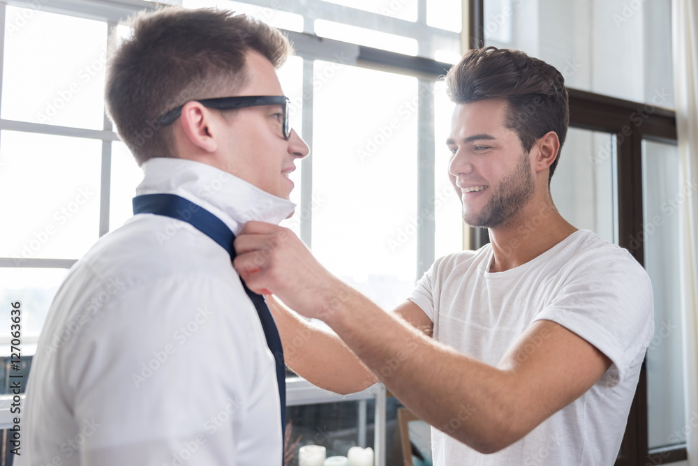 Obraz premium Handsome man tying his boyfriends necktie