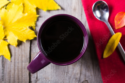 Cup of coffee surounded by red, purple and yellow fall leaves © eight8