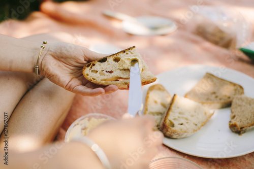 A woman buttering a slice of bread during a pic nic. photo