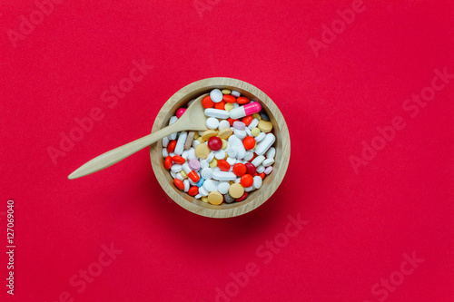 Top view colorful medicine and wood spoon,bowl on red background