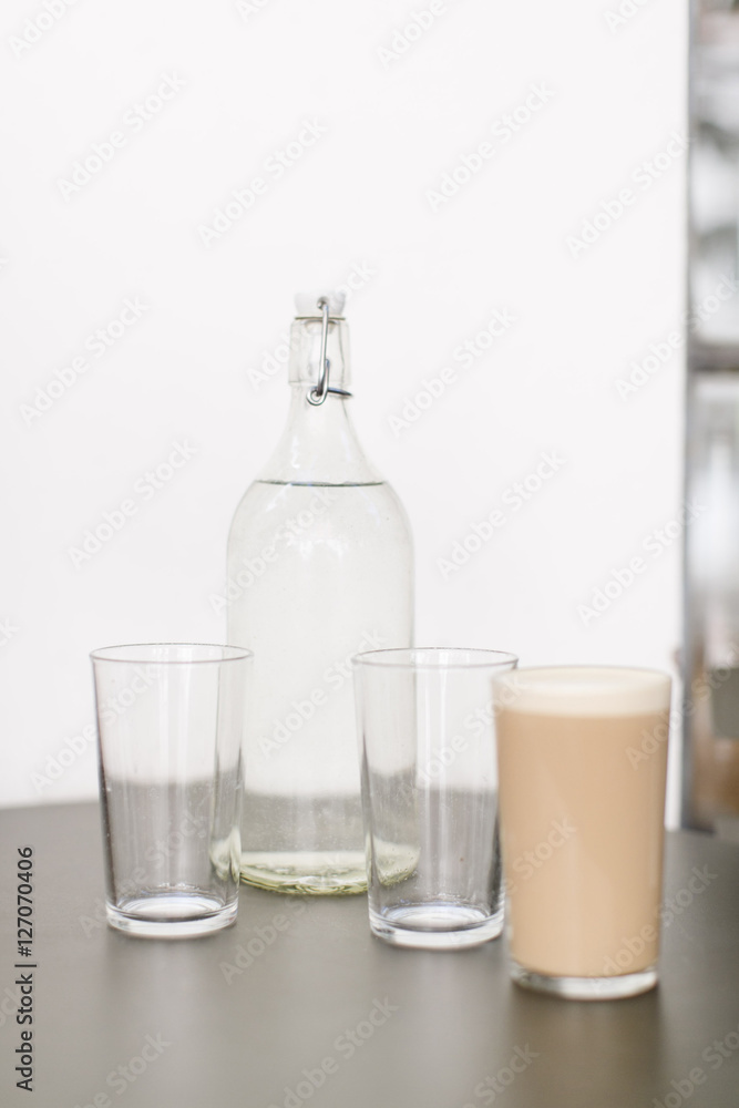 Glasses with cafe latte, empty glasses and water bottle Glasses with cafe latte, empty glasses and water bottle