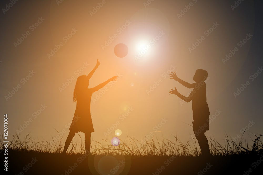 Silhouette children playing football on the sky sunset. Time on holiday Silhouette children playing football on the sky sunset. Time on holiday