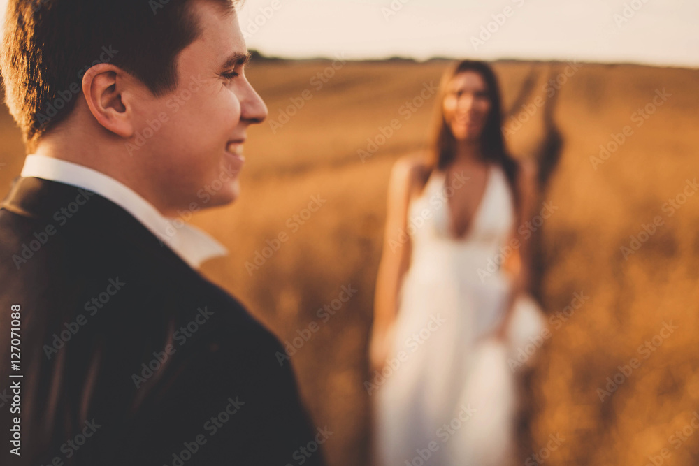 beautiful and young bride and groom standing in a field