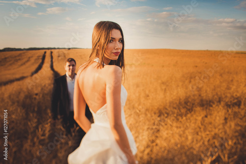 beautiful and young bride and groom standing in a field © pyrozenko13