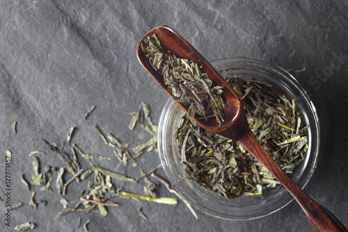 Bilde på lerret Glass jar with tea and wooden spoon on the dark stone background top view