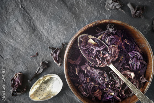 Fotografie Hibiscus tea in the wooden bowl on the dark stone background top view