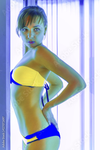 Slim woman in solarium getting sun tan