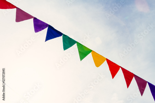Celebration color pennants against clouds in the sky with sunshi photo