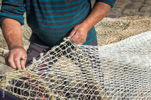 Hands of commercial fisherman mending nets