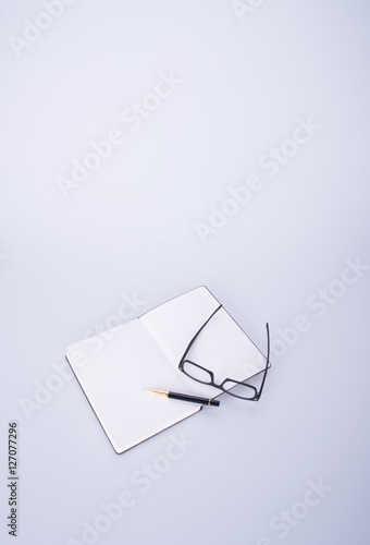 notebook with glasses and pen on the blackground. © heinteh