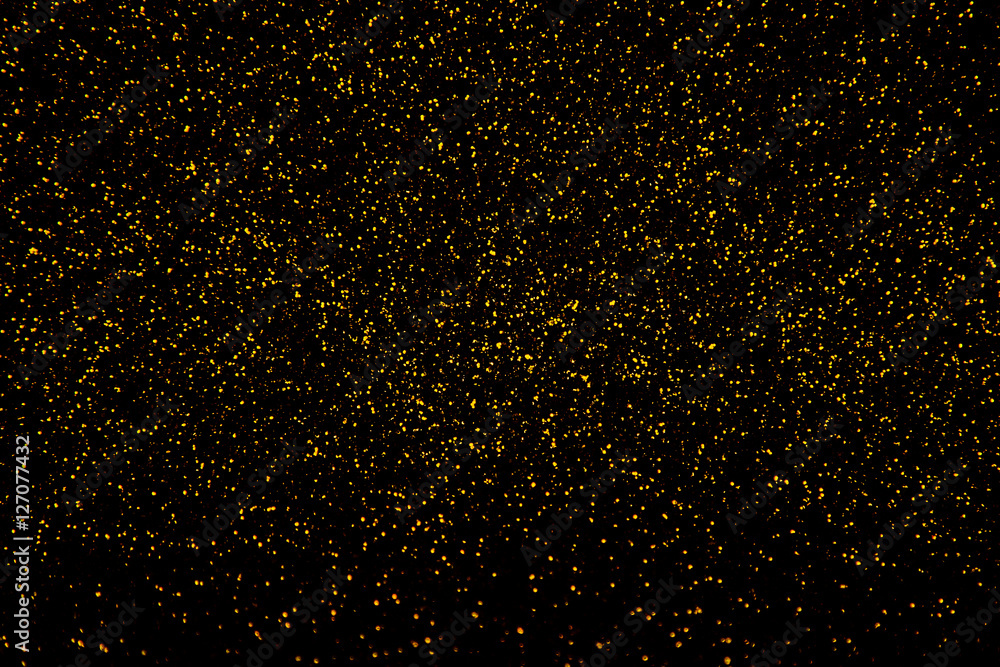 Gold glitter glowing on black background