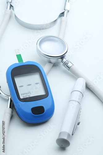 Blood glucose meter and stethoscope on white background