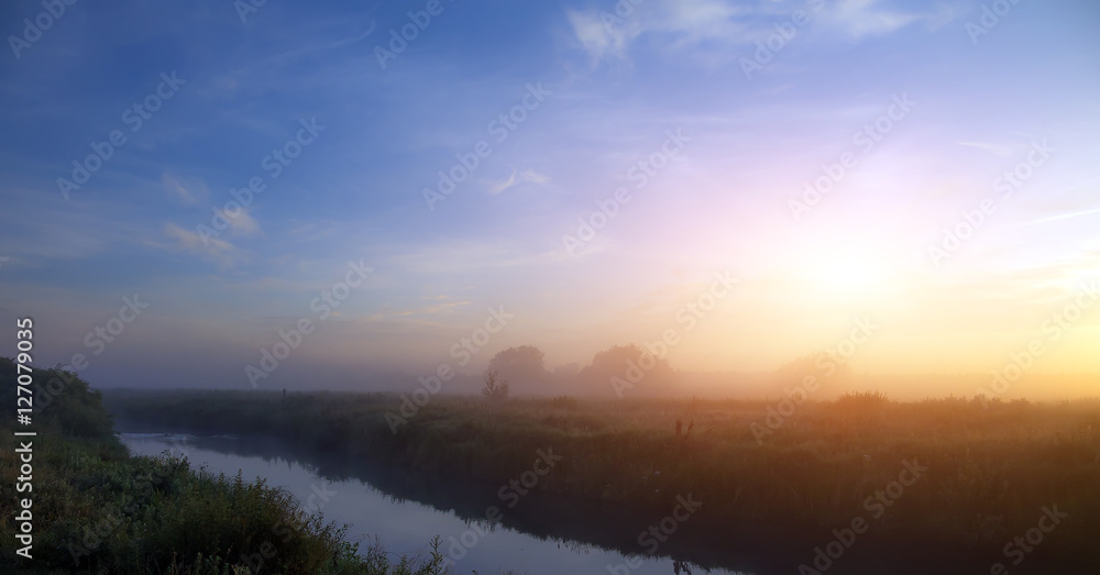 wonderful dramatic scene. fantastic foggy sunrise over the meadow with colorful clouds on the sky. picturesque rural landscape, misty morning. color in nature. beauty in the world