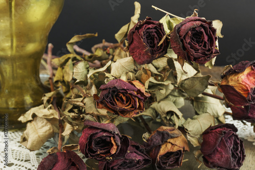Dry roses with vase on black background