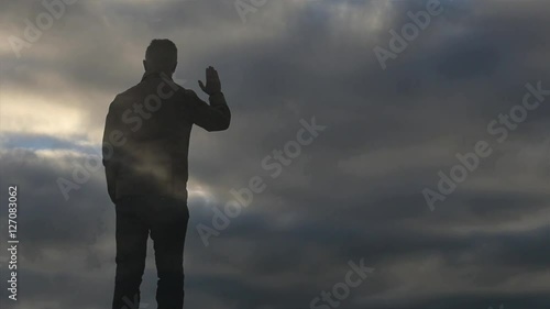 Mans silhouette dissolving on sky background slow motion photo