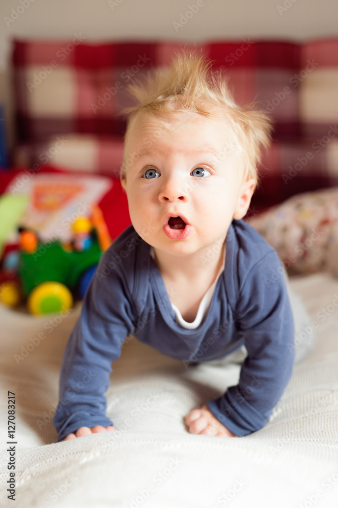 Fototapeta premium Little baby boy with spiky hair crawling on bed.