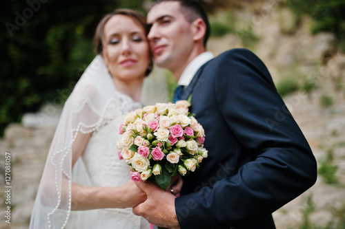 Close up portrait of wedding couple. Focus on wedding bouquet of