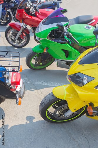 red green and yellow motorcycle in parking lot in row close up © Yuri Bizgaimer