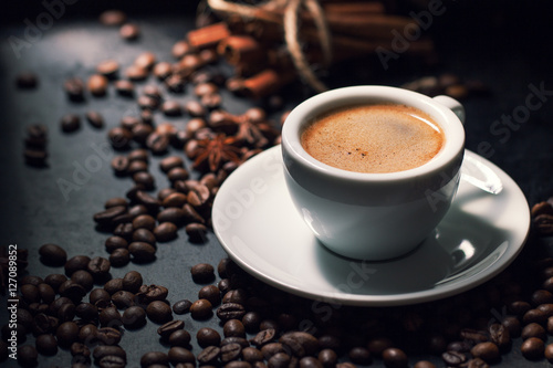 Fresh tasty espresso cup of coffee with coffee beans on dark bac