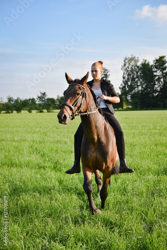 Teenager reitet mit Pferd auf einer Wiese, Hochformat