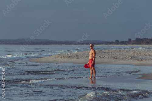 lifeguard on the beach with glasses, with a life buoy, wet sand and sea at sunset
