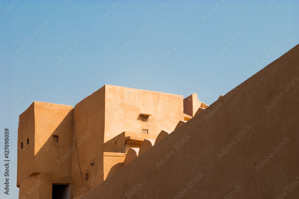 Minimal shot of beautiful light falling on clay building in India against blue sky
