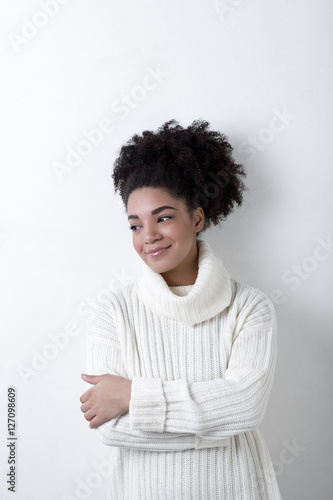 Young woman in a white knit sweater hugging herself