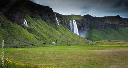 Dark cliff with waterfalls in Iceland and grass