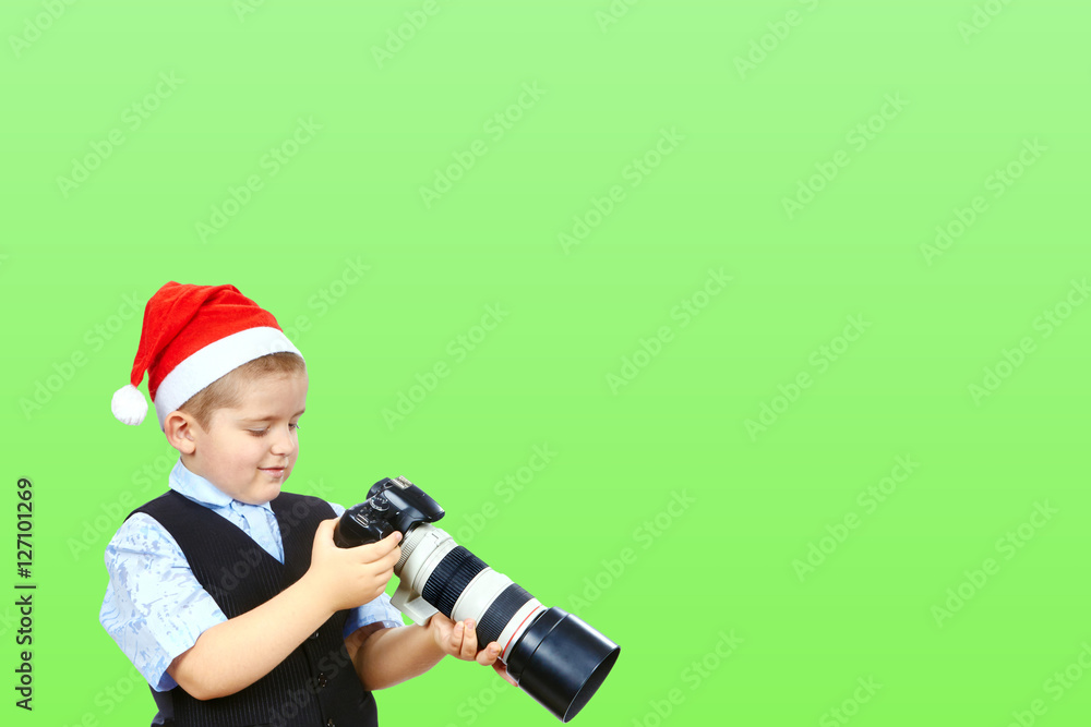 On a green background a little photographer in cap of Santa Claus On a green background a little photographer in cap of Santa Claus