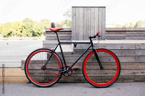 Red bycicle parked near bench in park