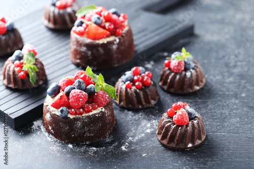 Sweet chocolate cakes with berries on black wooden table