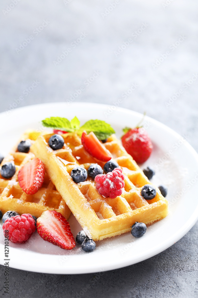 Homemade waffles with berries in plate on grey table Homemade waffles with berries in plate on grey table