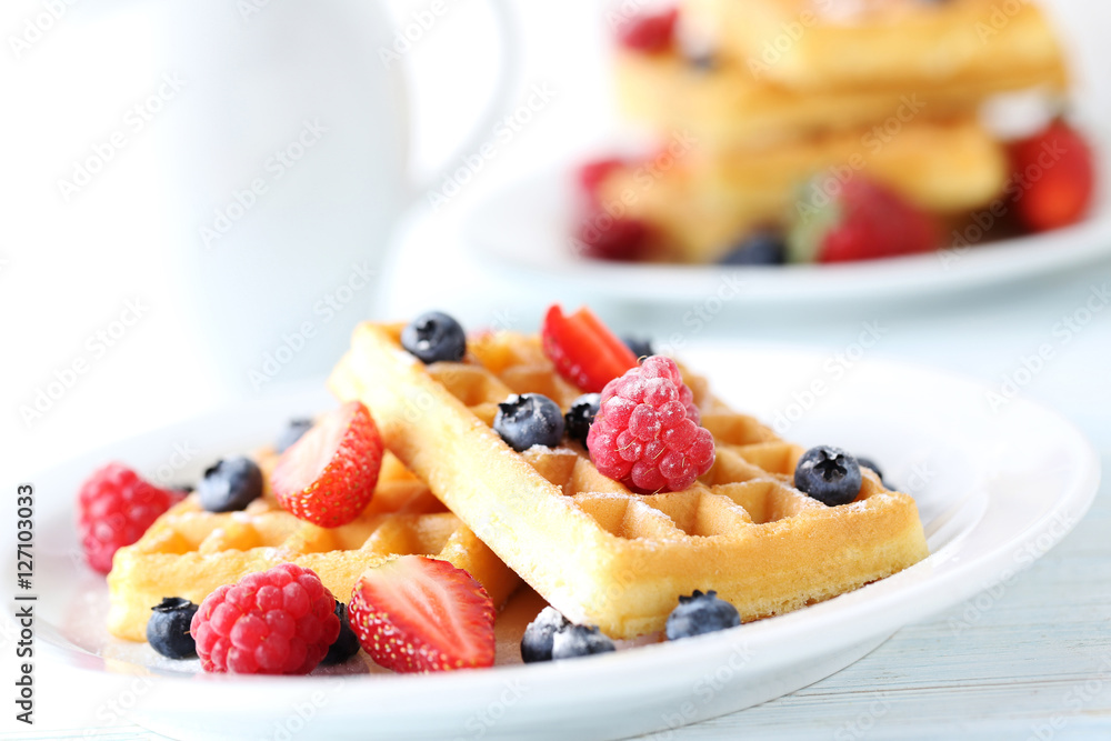 Homemade waffles with berries in plate on blue wooden table Homemade waffles with berries in plate on blue wooden table